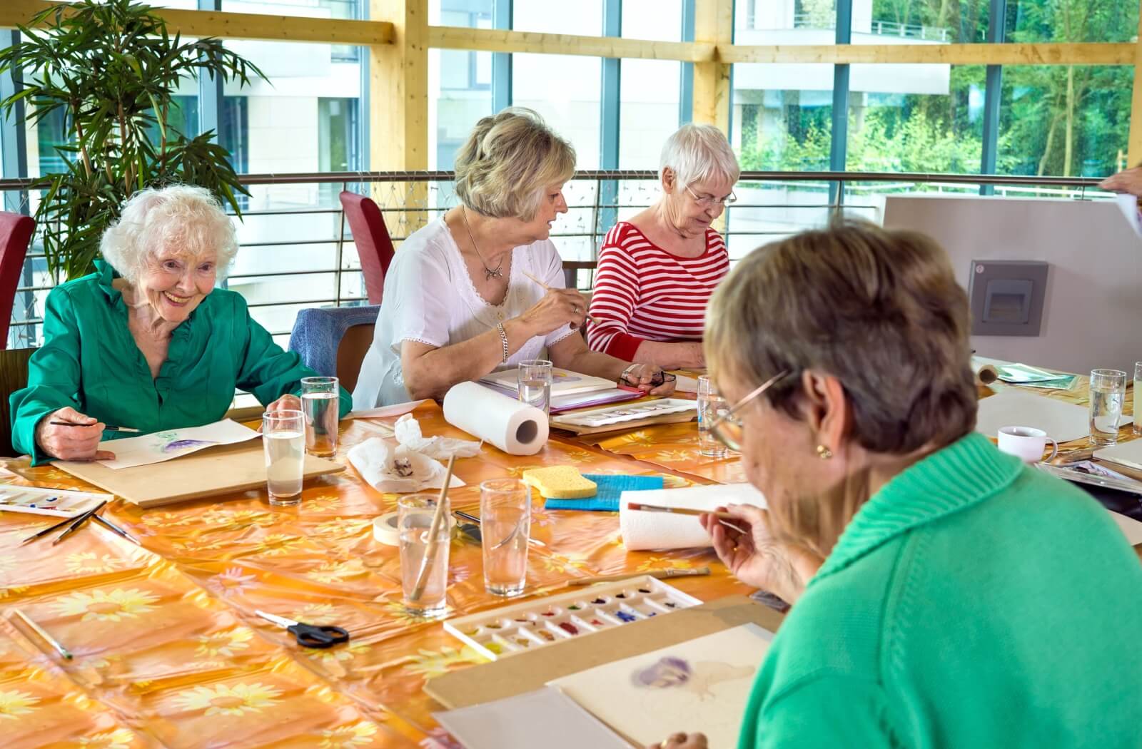 A group of older adult women painting together at a table.