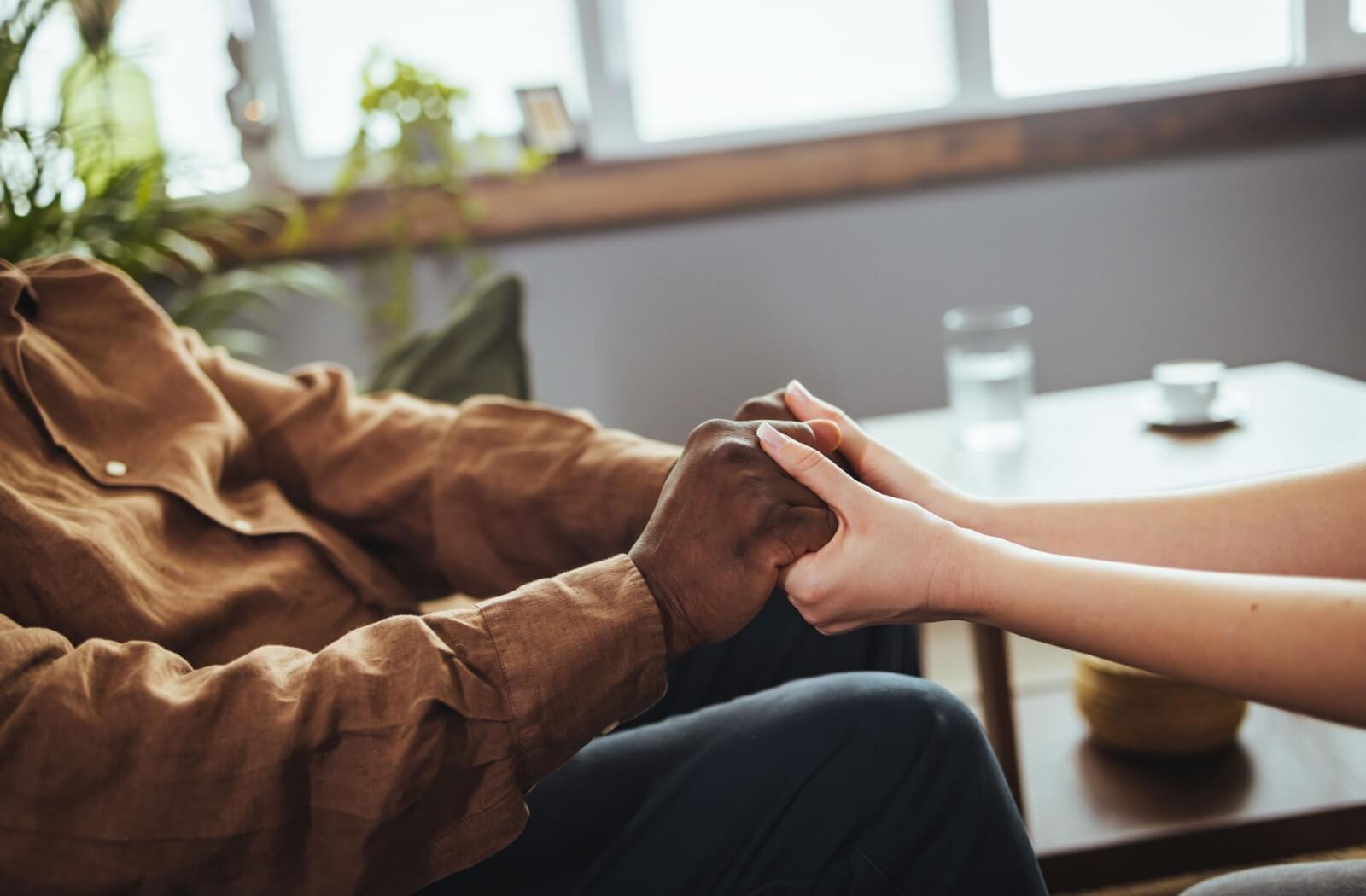 A nurse holds the hands of a person with Parkinson's disease.