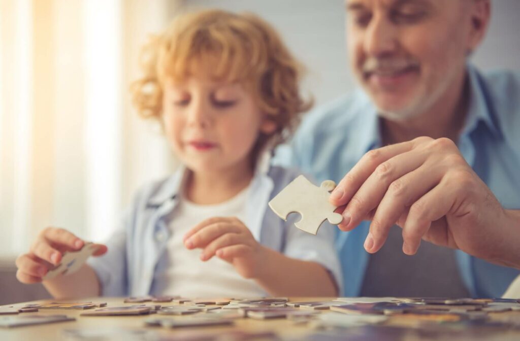 An older man and his grandchild build a puzzle together.