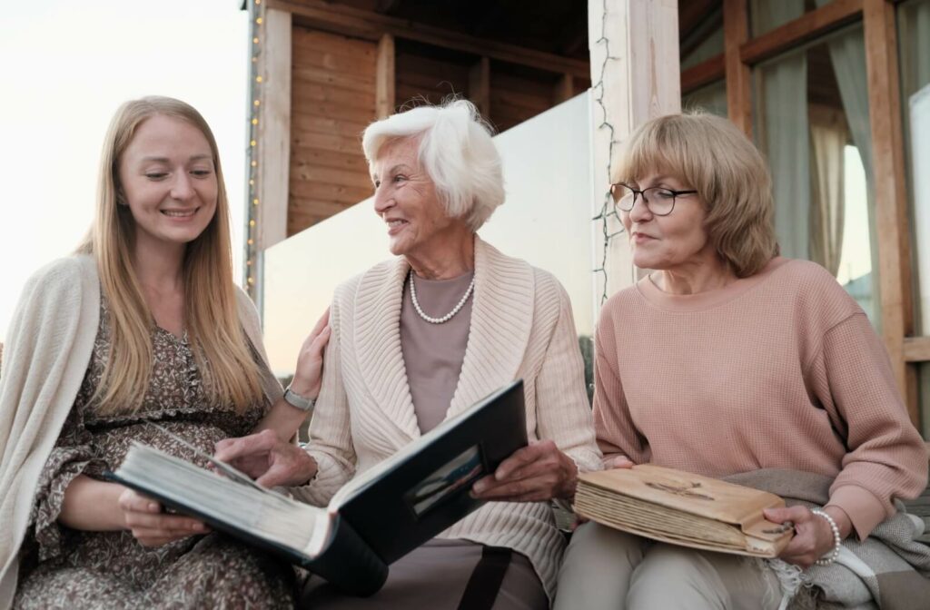 An older adult sits looking at an old photo album with their children, talking about memories and making new ones.