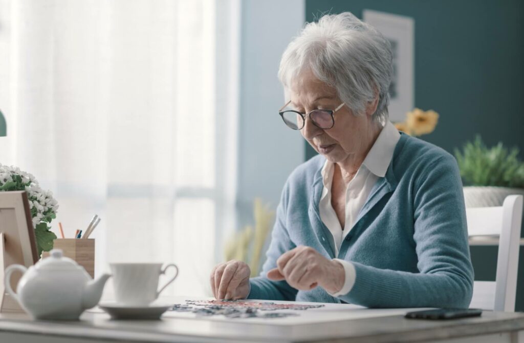 An older adult assembling a puzzle as a memory exercise in their kitchen in senior living.