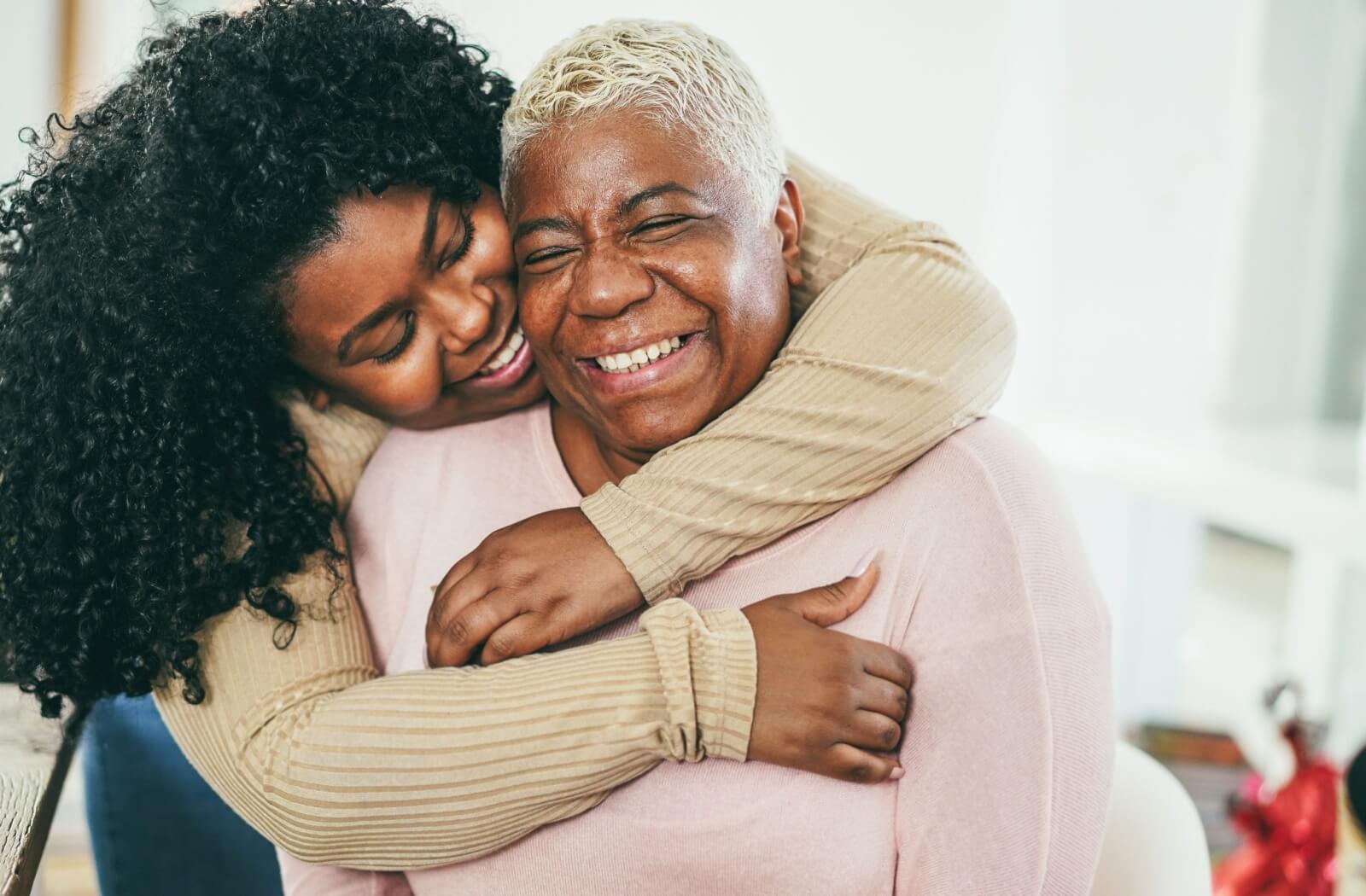 An adult hugging their older adult parent in assisted living.