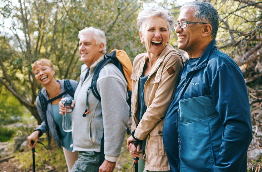 A group of older adults laugh together during a hike in the woods.