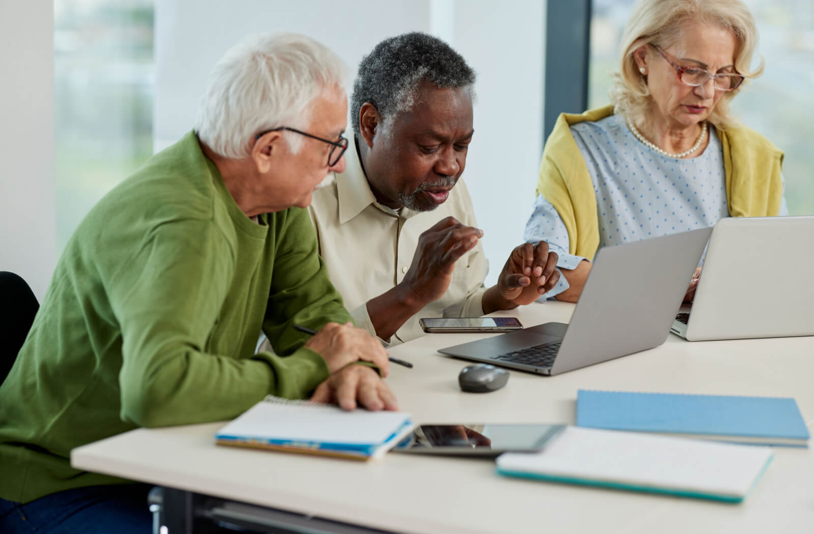 3 seniors working on project using a laptop in classroom.